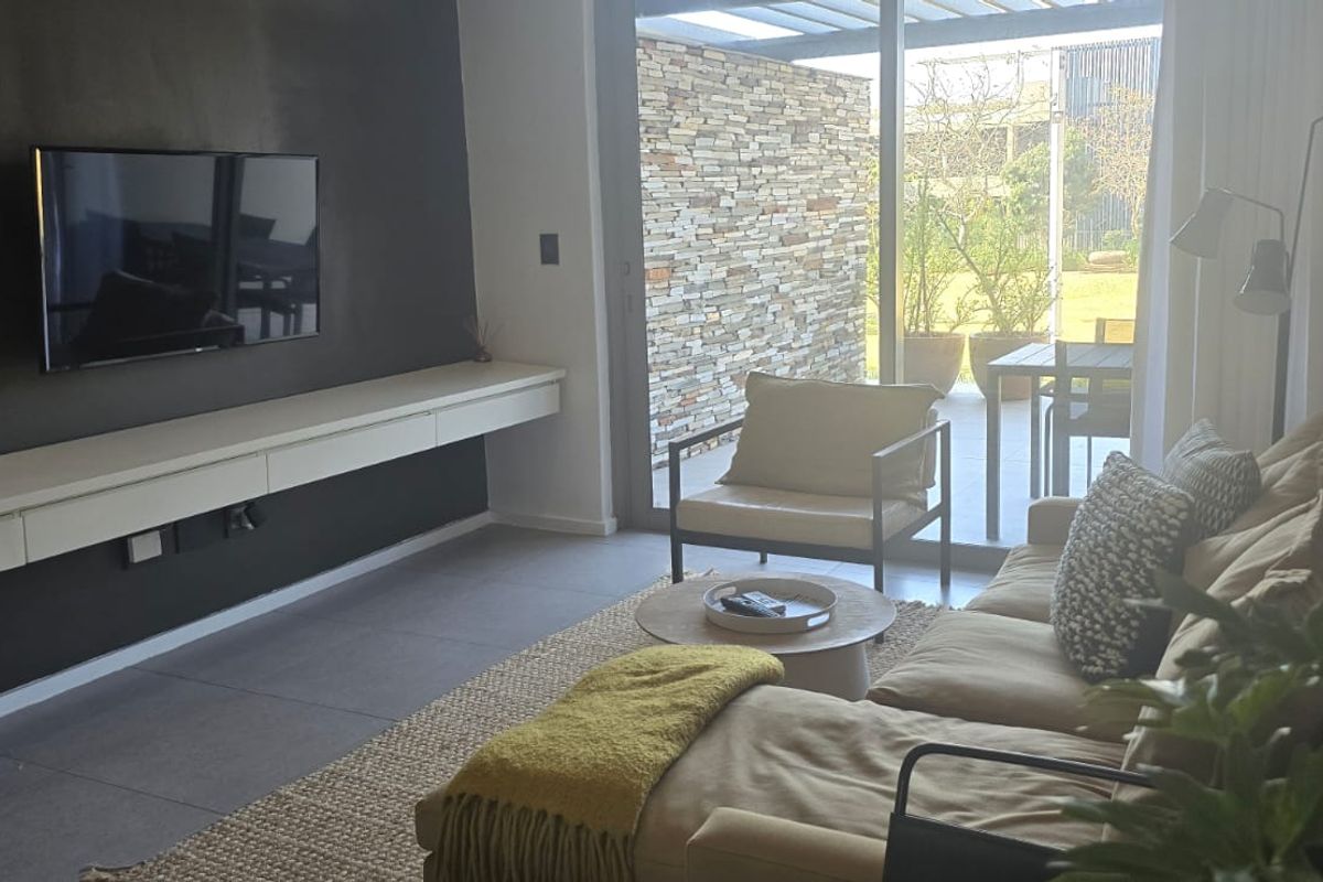 Modern living room featuring a sleek floating media console, large sliding glass doors, and seamless access to an outdoor patio area.