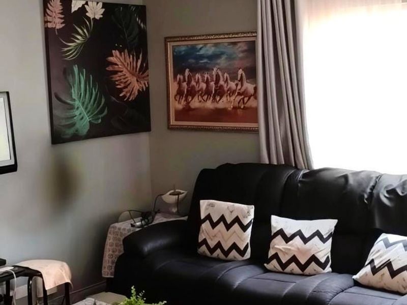 A comfortable living room space featuring neutral wall tones, coving, and natural light through window treatments.