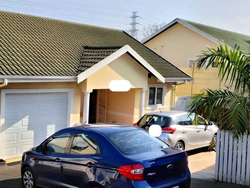 Front elevation of a single-story house featuring a tiled roof, integrated garage, and a covered entrance porch with a paved driveway.