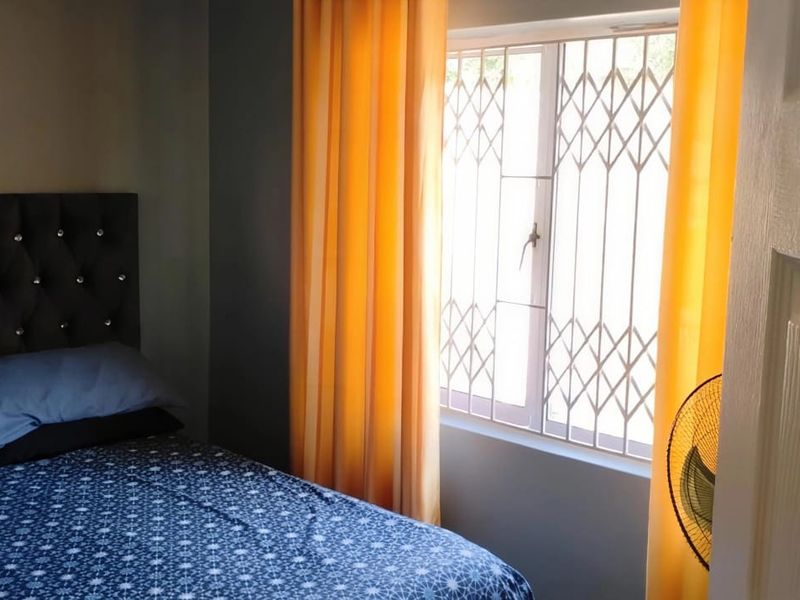 A bedroom featuring a window with a fitted security gate, providing natural light and ventilation.