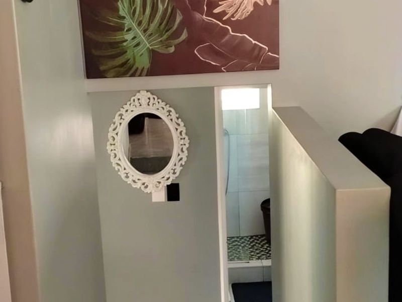 A neutral-toned hallway featuring tiled flooring and a half-height partition wall leading towards a secondary space.
