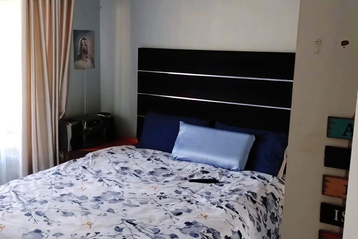 A standard bedroom featuring a window with curtains and a door, showing signs of minor wall surface wear.