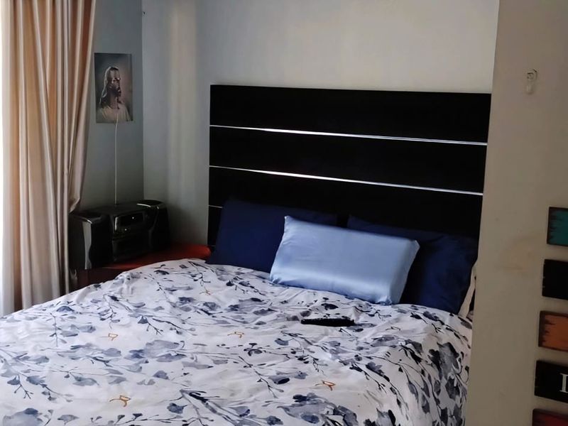 A standard bedroom featuring a window with curtains and a door, showing signs of minor wall surface wear.
