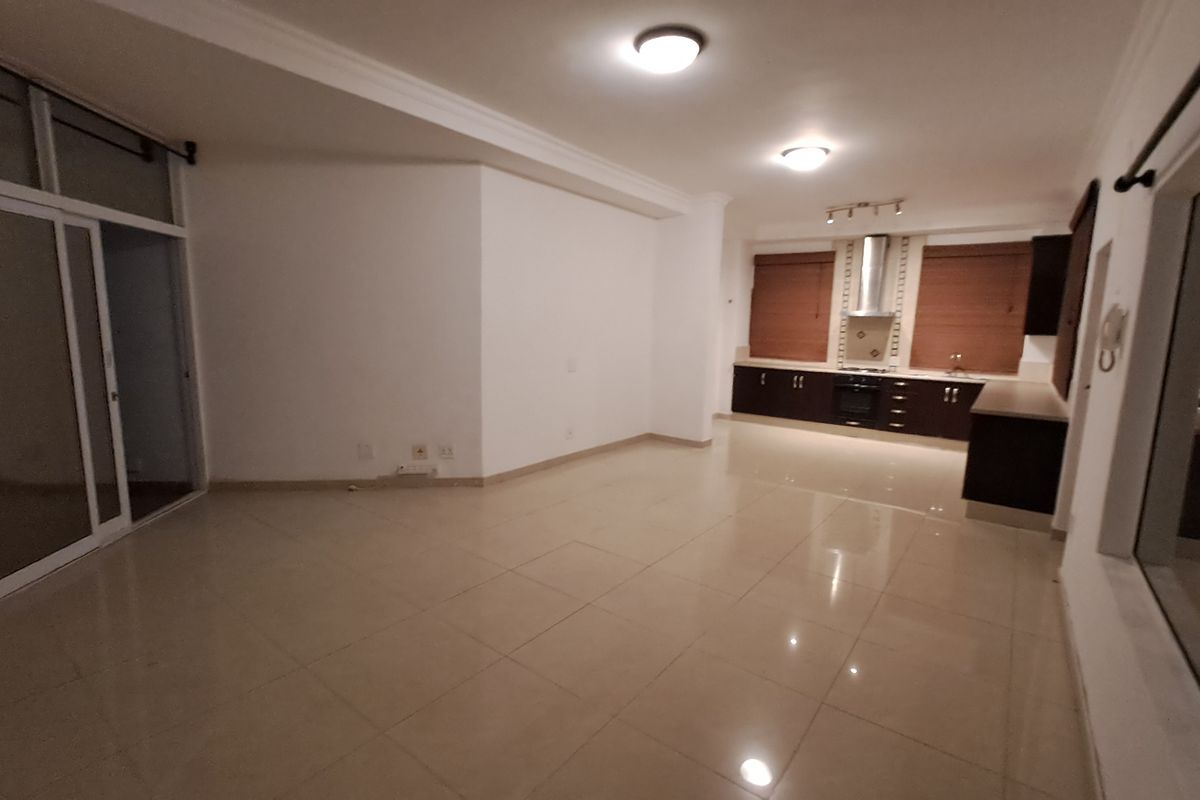 Spacious open-plan living and kitchen area featuring tiled floors, modern cabinetry, built-in oven, extractor fan, and large sliding doors leading to an outdoor space.