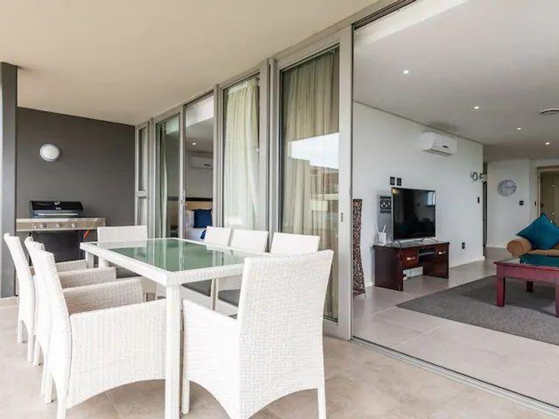 Spacious covered balcony featuring tiled flooring, recessed lighting, and a built-in outdoor grill, seamlessly connecting to the interior living area through large sliding doors.
