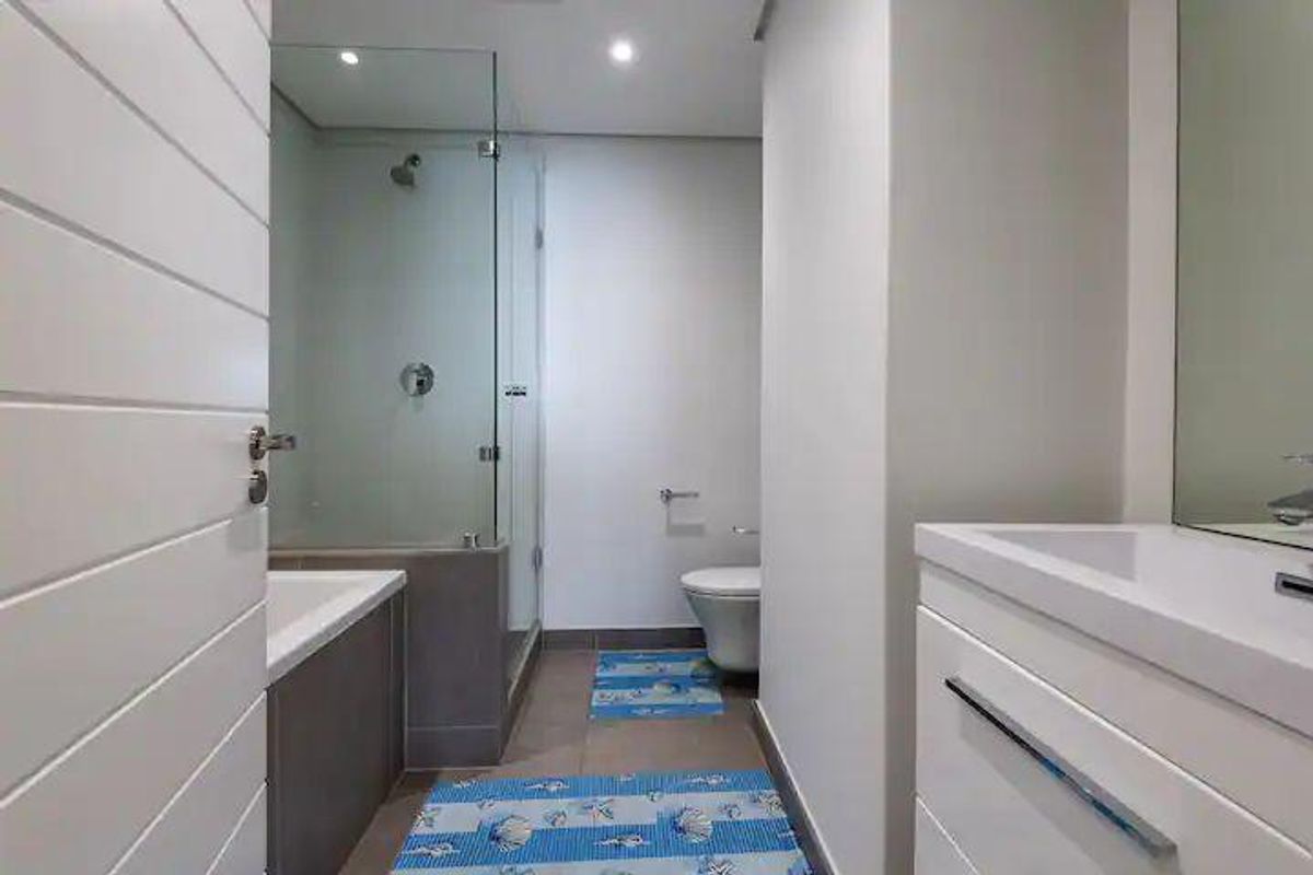 Modern bathroom featuring a glass-enclosed shower, built-in bathtub, wall-mounted toilet, and a sleek vanity cabinet with an integrated sink.
