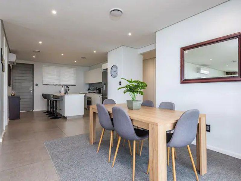 Modern open-plan living and dining area featuring tiled floors, recessed lighting, and a functional kitchen island with breakfast bar seating.