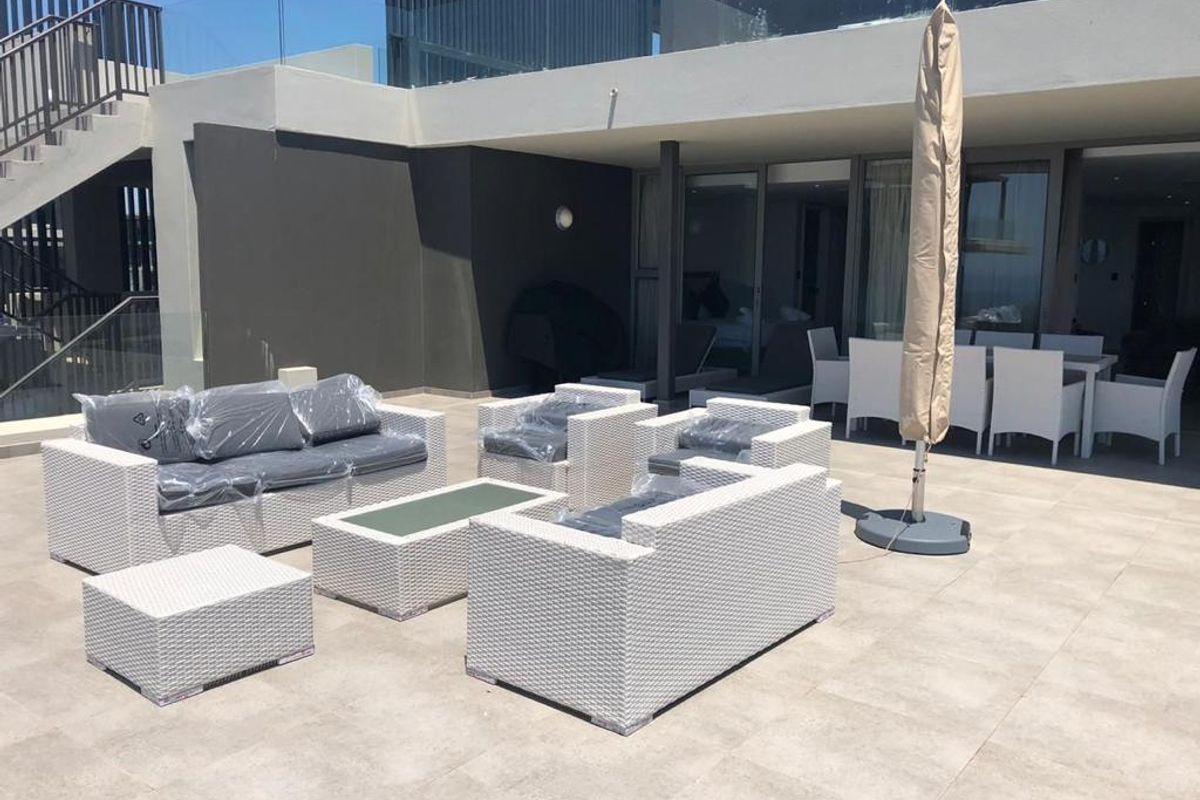 Spacious outdoor patio area featuring modern tiled flooring, glass balustrades, and direct access to the interior through large sliding glass doors.