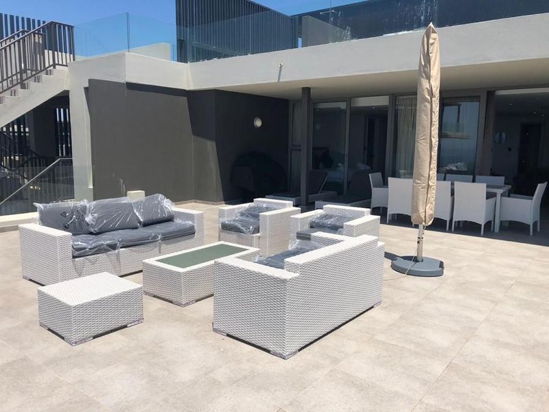 Spacious outdoor patio area featuring modern tiled flooring, glass balustrades, and direct access to the interior through large sliding glass doors.