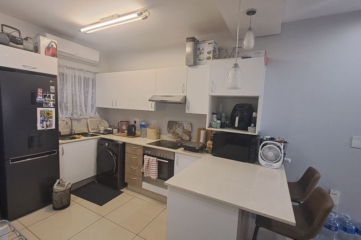 A functional kitchen featuring built-in cabinetry, stone countertops, integrated oven and hob, and tiled flooring, providing a practical and efficient cooking space.