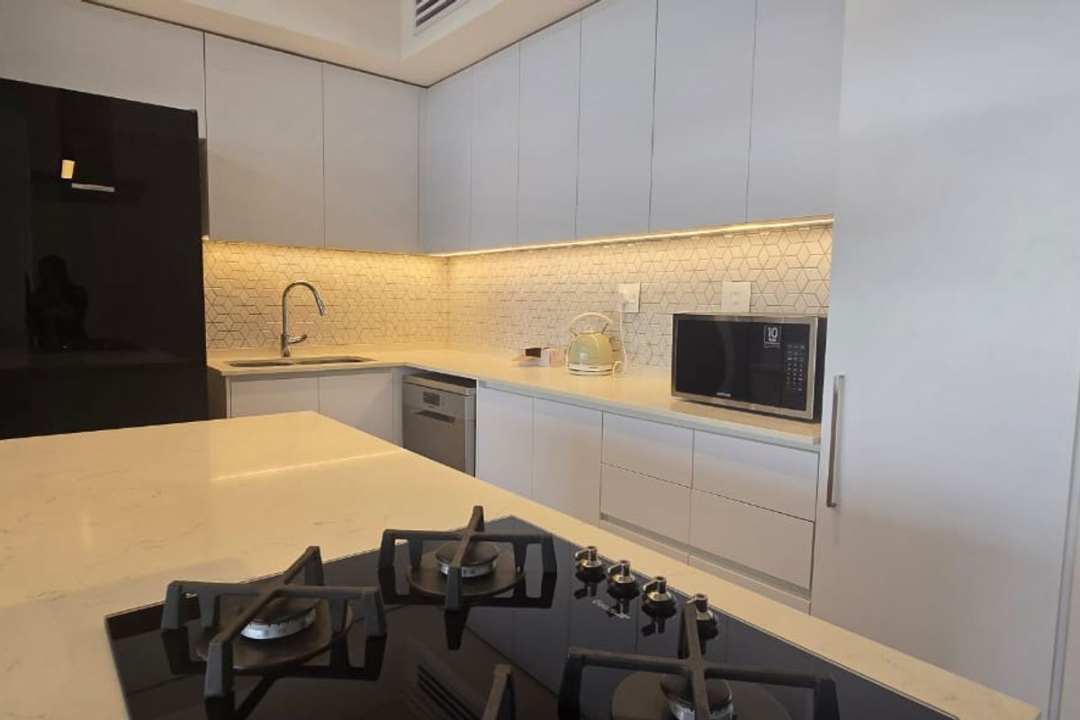 Modern kitchen featuring sleek white cabinetry, stone countertops, a central island with a gas hob, and a stylish geometric tiled backsplash.
