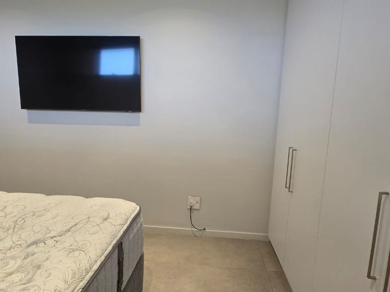 A modern bedroom featuring neutral tiled flooring, built-in white cabinetry, and a clean, minimalist aesthetic.