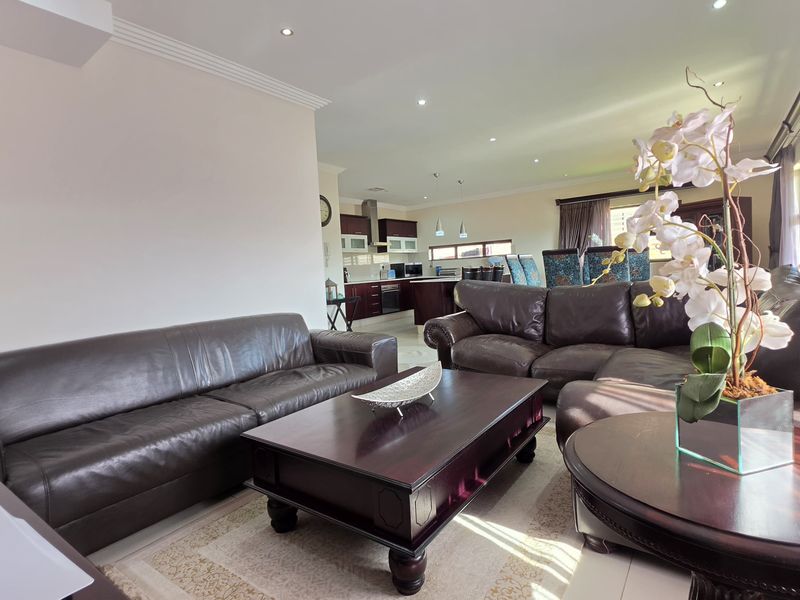Spacious open-plan living area featuring tiled floors, recessed lighting, and a modern kitchen with dark cabinetry and a central island.