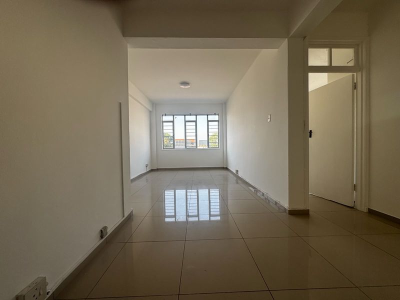 A bright, vacant living area featuring neutral tiled flooring and large windows, providing a clean and versatile space ready for personalization.