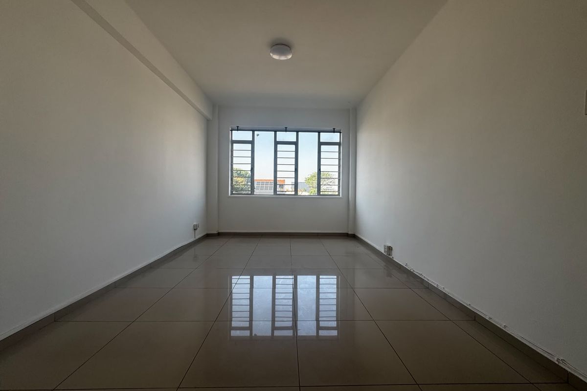 A bright, empty living room featuring neutral tiled flooring and a large window, providing a clean canvas for interior design and personalization.
