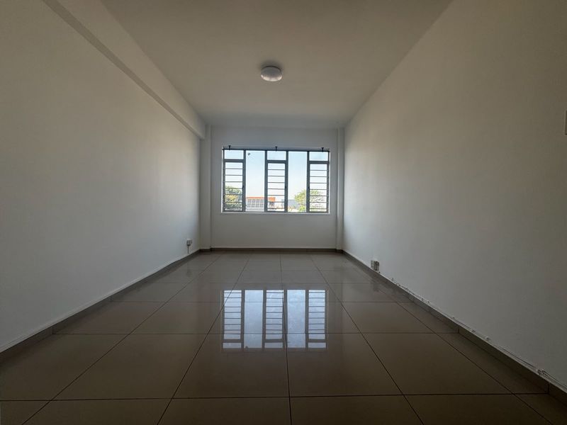 A bright, empty living room featuring neutral tiled flooring and a large window, providing a clean canvas for interior design and personalization.