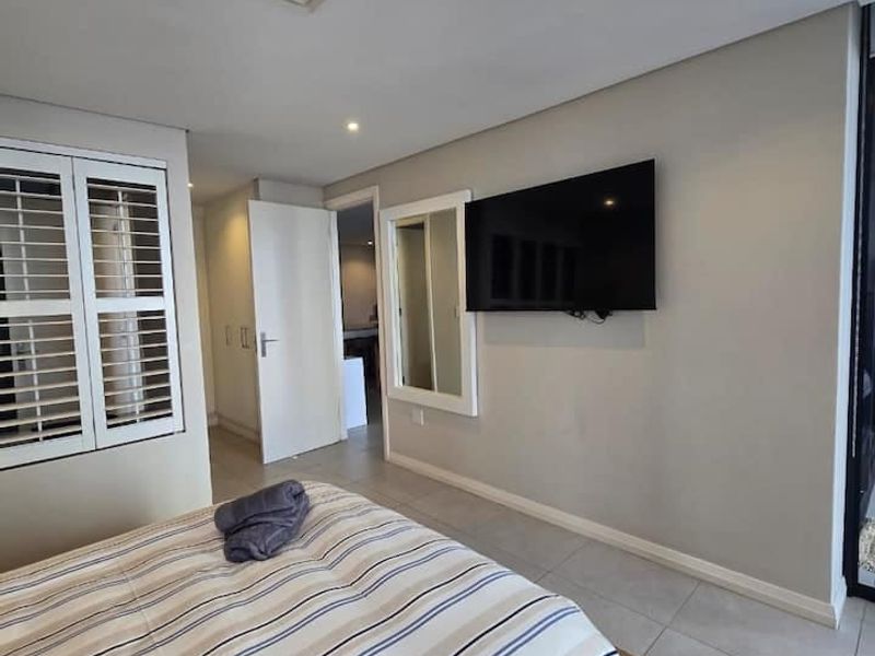 A well-maintained bedroom featuring tiled flooring, plantation shutters, and a recessed ceiling air conditioning vent.