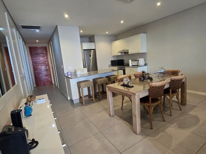 Open-plan living and dining area featuring tiled floors, recessed lighting, ducted air conditioning, and a modern kitchen with stone countertops.