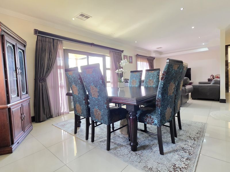 Spacious open-plan dining and living area featuring tiled flooring, recessed downlighting, and large sliding glass doors leading to the exterior.