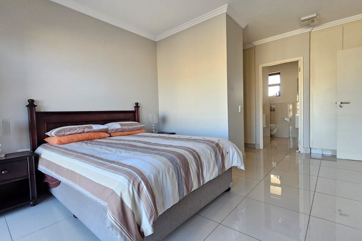 Spacious bedroom featuring tiled flooring, built-in cupboards, and direct access to an en-suite bathroom.