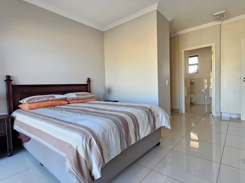 Spacious bedroom featuring tiled flooring, built-in cupboards, and direct access to an en-suite bathroom.