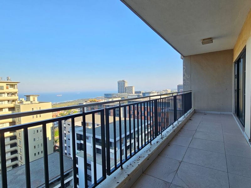 Spacious apartment balcony featuring tiled flooring, a metal balustrade, and expansive urban and sea views.