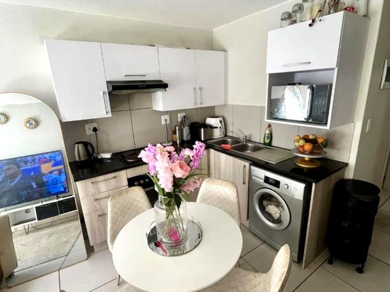 Compact kitchen featuring white cabinetry, dark countertops, integrated appliances, and tiled flooring, designed for efficient use of space in an apartment setting.