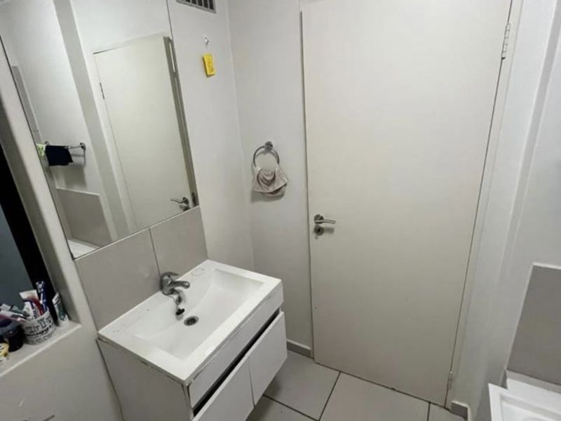 A clean and functional bathroom featuring a modern wall-mounted vanity with a ceramic basin, large mirror, and neutral floor tiling.