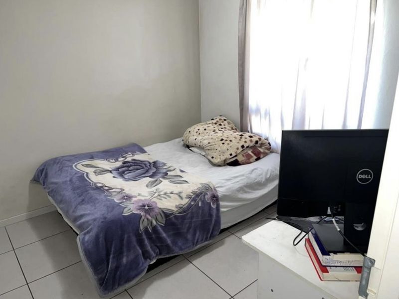 A standard bedroom featuring tiled flooring and natural light from the window, providing a functional space for rest.