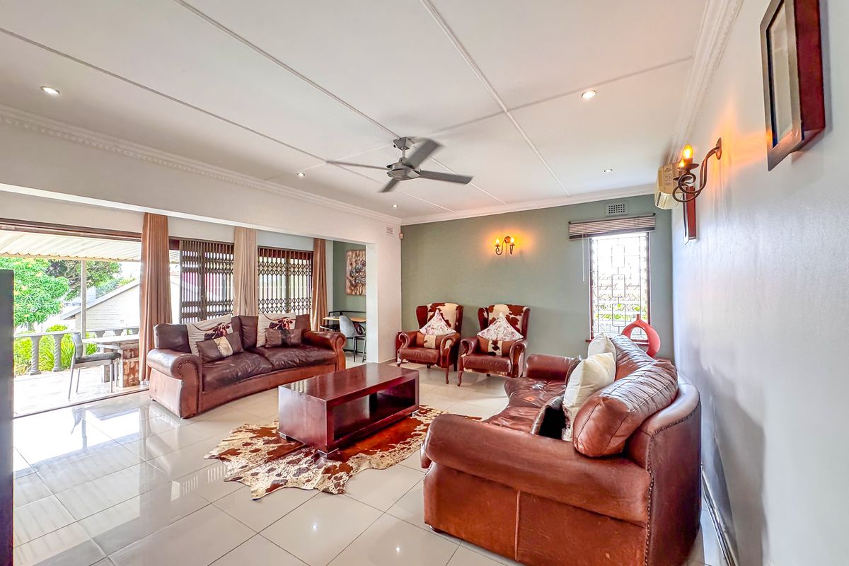Spacious living room featuring tiled flooring, ceiling fan, and direct access to an outdoor patio area through sliding glass doors.