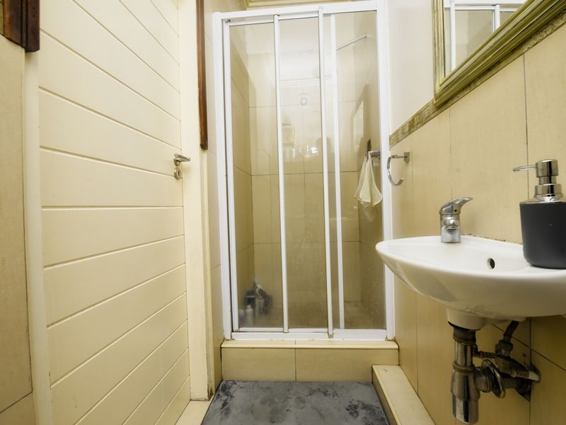 A compact bathroom featuring a shower enclosure, wall-mounted basin with mixer tap, and tiled finishes throughout.