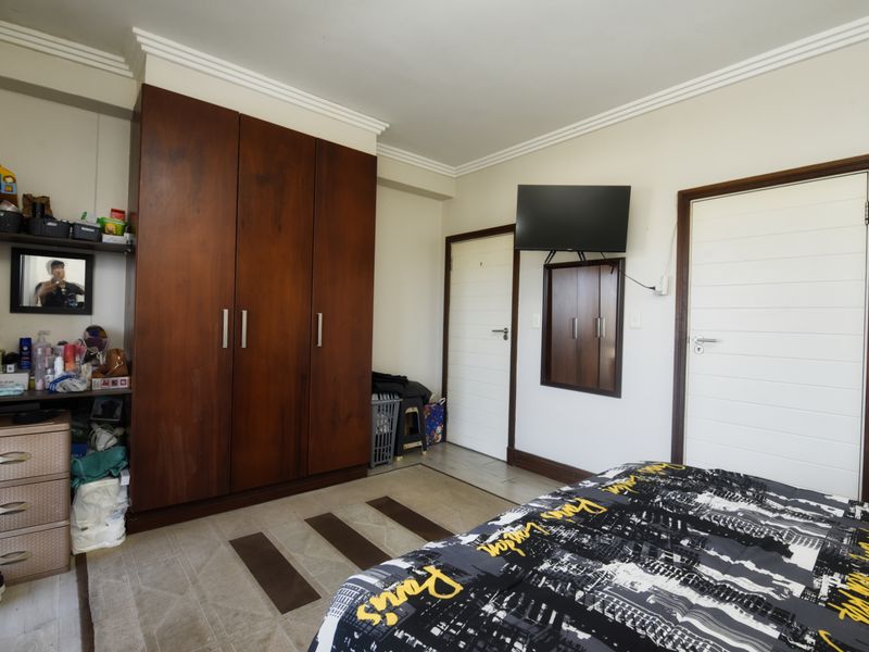 A bedroom featuring a large built-in wooden wardrobe, crown molding, and two internal doors.