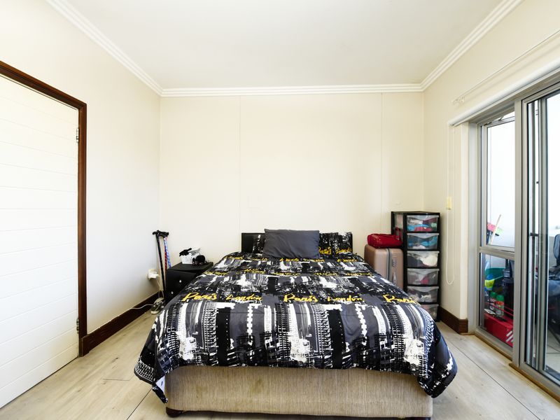 A bedroom featuring laminate flooring, coving, and a sliding glass door providing access to an outdoor area.