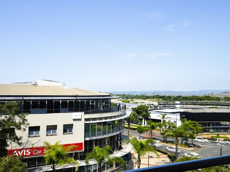 Elevated urban view overlooking surrounding commercial buildings, road infrastructure, and distant landscape.
