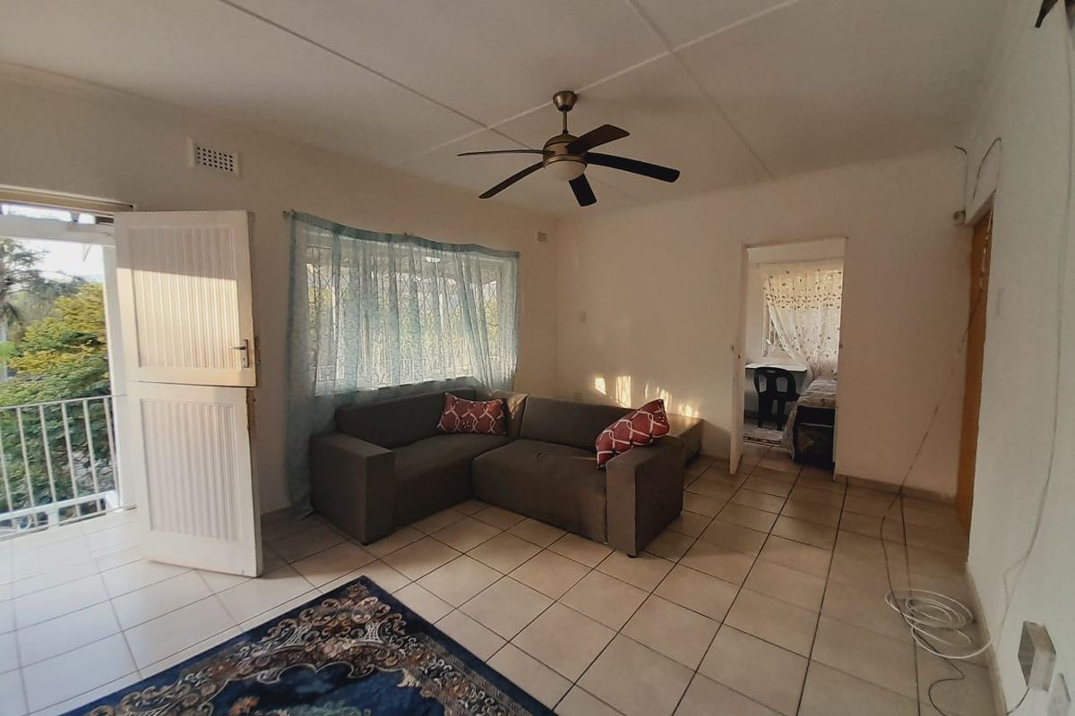 A living room featuring tiled flooring, a ceiling fan, and direct access to a balcony through a door.