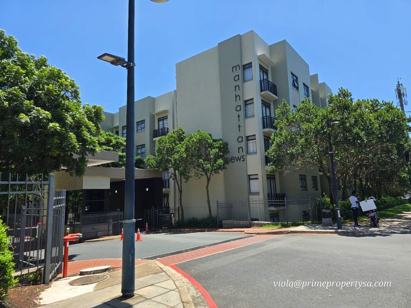 Exterior view of the Manhattan Mews apartment complex, featuring modern building architecture, secure gated entrance, and landscaped surroundings.