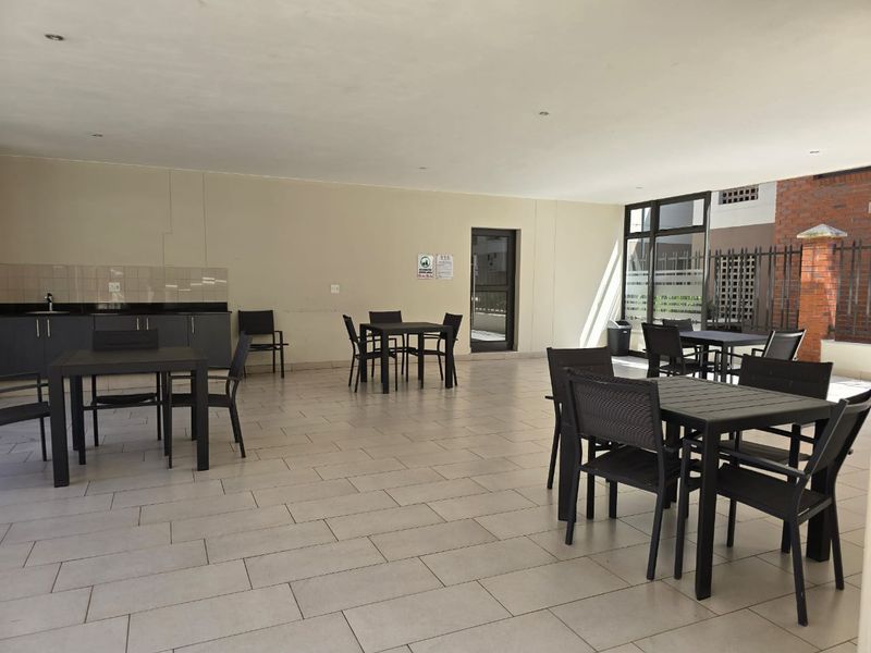 A spacious covered patio area featuring tiled flooring, a built-in kitchenette with sink and granite countertops, suitable for outdoor entertaining.