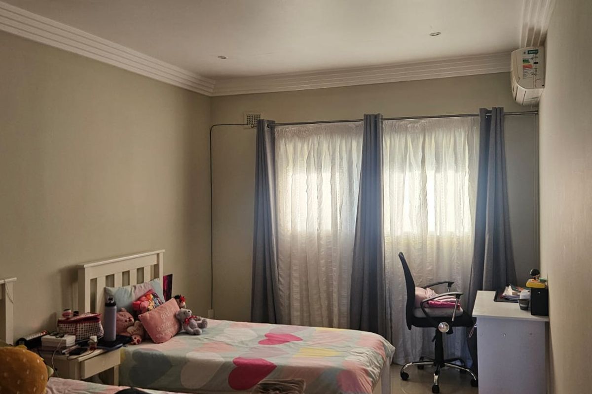 A functional bedroom featuring crown molding, recessed lighting, and a wall-mounted air conditioning unit, providing a comfortable living space.