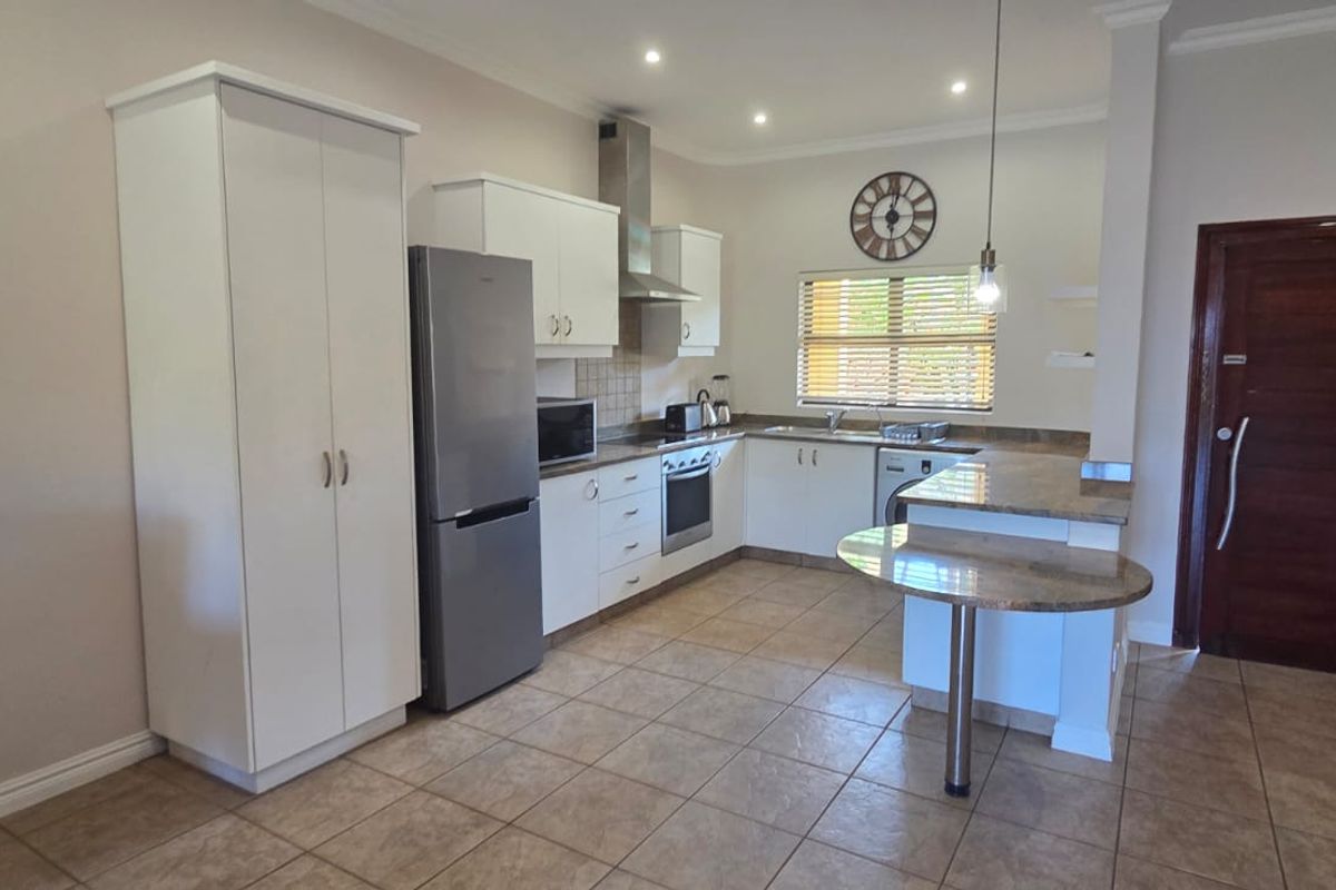 A functional kitchen featuring white cabinetry, granite countertops, a breakfast nook, and built-in appliances, finished with tiled flooring and recessed lighting.