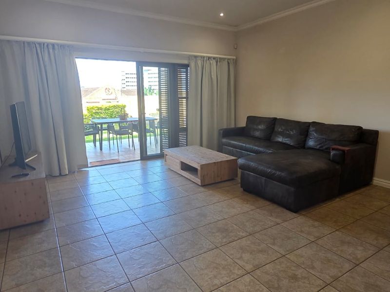 Spacious open-plan living and dining area featuring neutral tiled flooring and large sliding glass doors providing direct access to the outdoor patio.