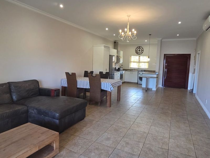 Spacious open-plan living and dining area featuring tiled floors, recessed lighting, and a functional kitchen with built-in cabinetry and appliances.