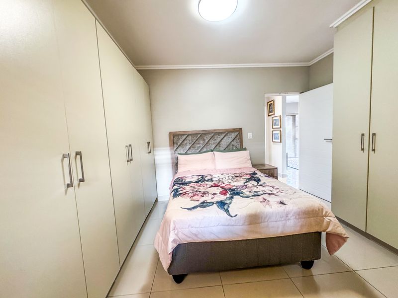 A well-maintained bedroom featuring extensive built-in cabinetry, neutral tiled flooring, and clean finishes, offering ample storage space.