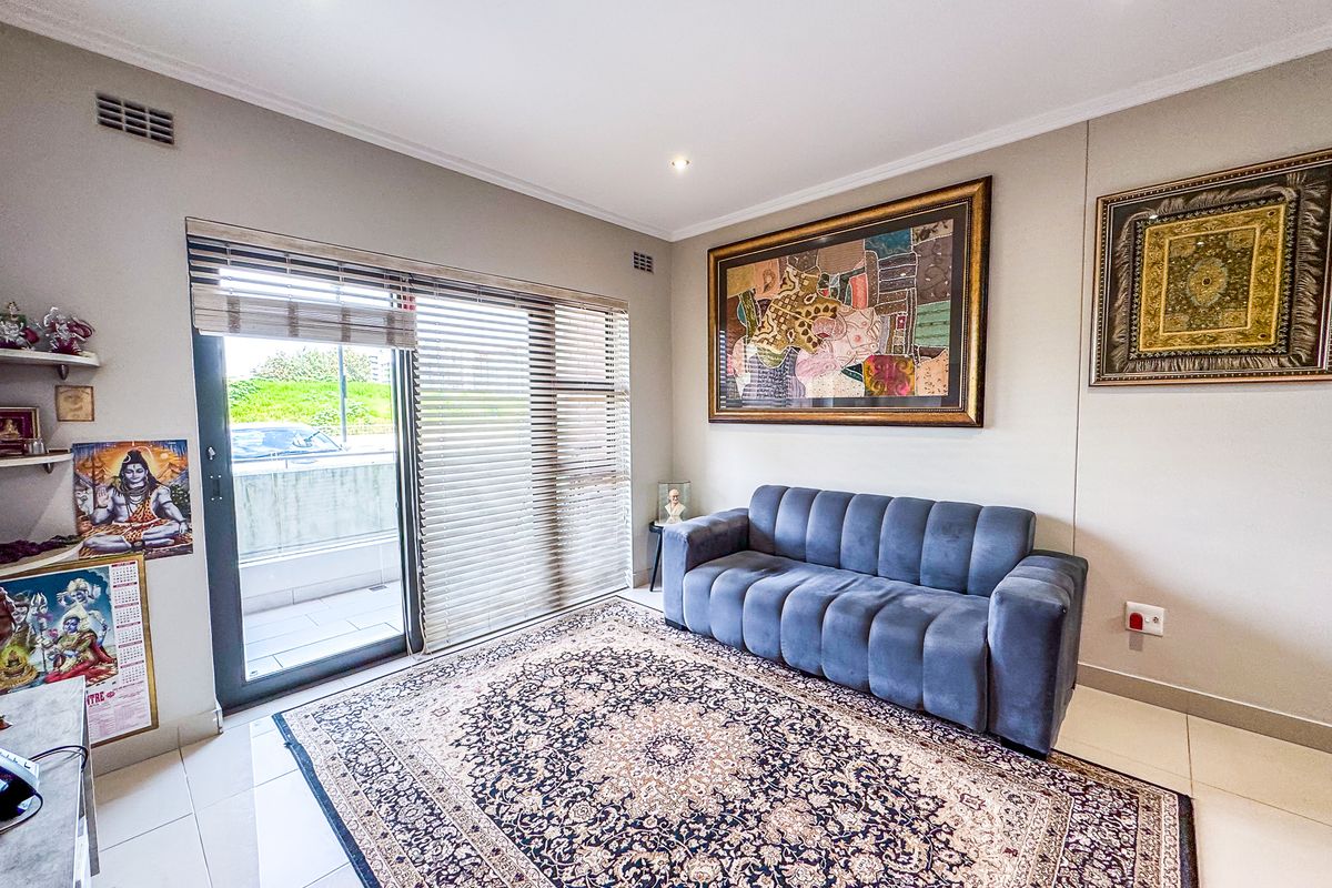 A bright living room featuring tiled flooring, recessed downlights, and a large sliding glass door providing access to an outdoor balcony area.