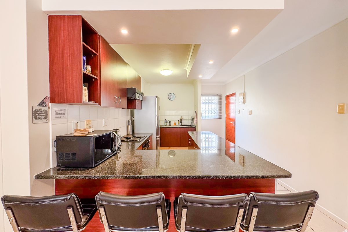 A functional kitchen featuring dark wood cabinetry, granite countertops, and a breakfast bar, providing a practical layout for cooking and casual dining.