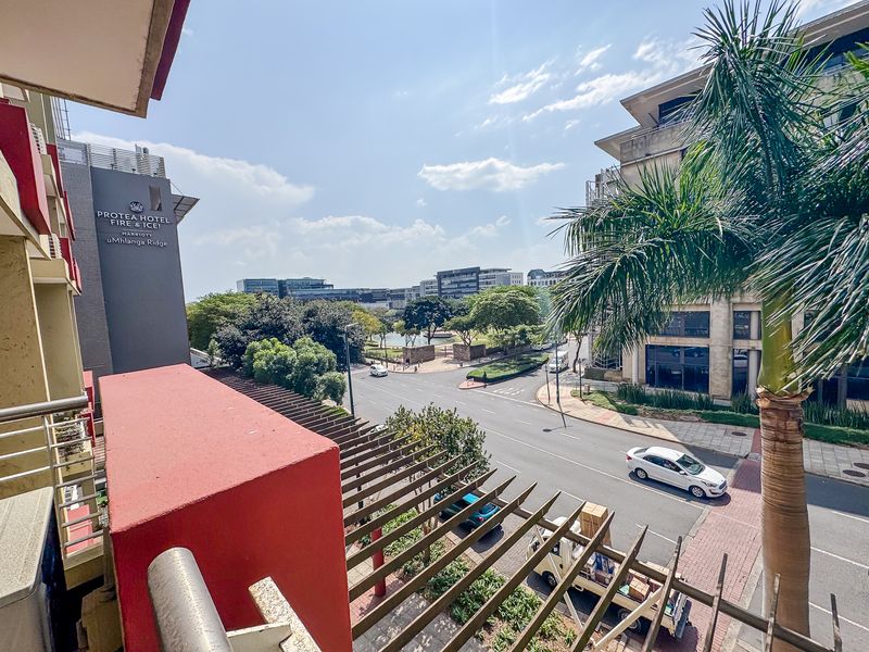 Elevated urban view overlooking the street, surrounding commercial buildings, and local landscape from a private balcony.