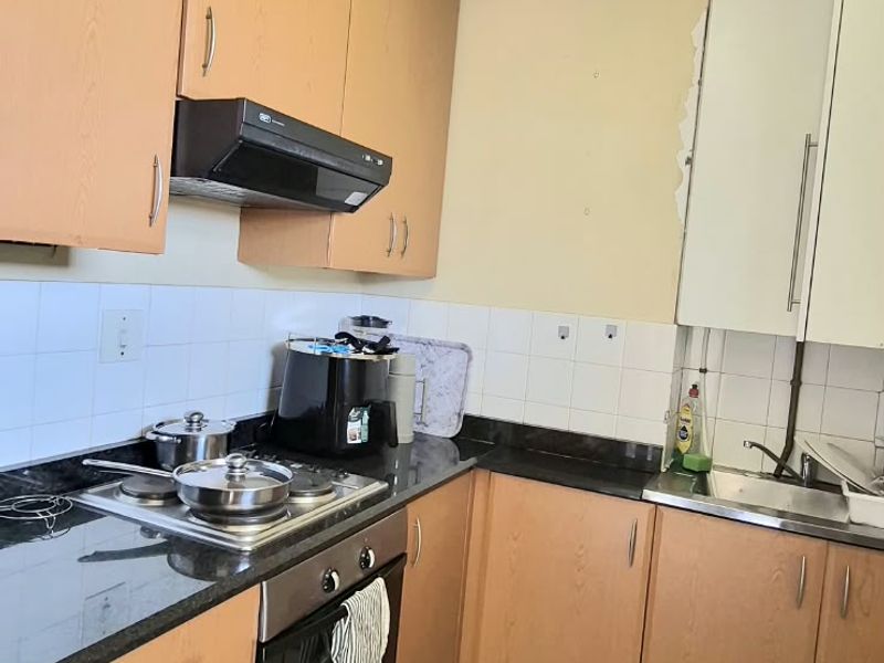 Functional kitchen featuring laminate cabinetry, granite countertops, built-in oven, electric hob, and tiled flooring. The space offers a practical layout for daily meal preparation.