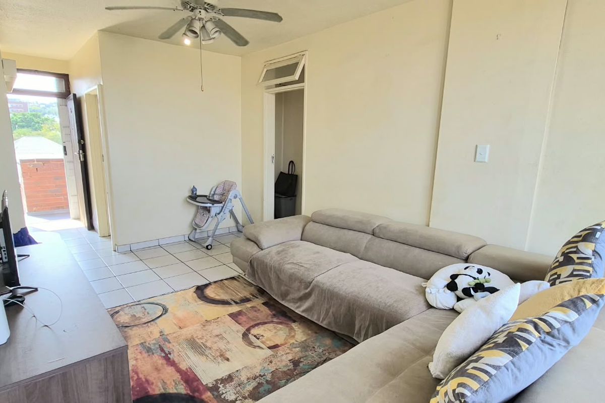 A living room featuring tiled flooring, a ceiling fan, and access to an outdoor balcony area.