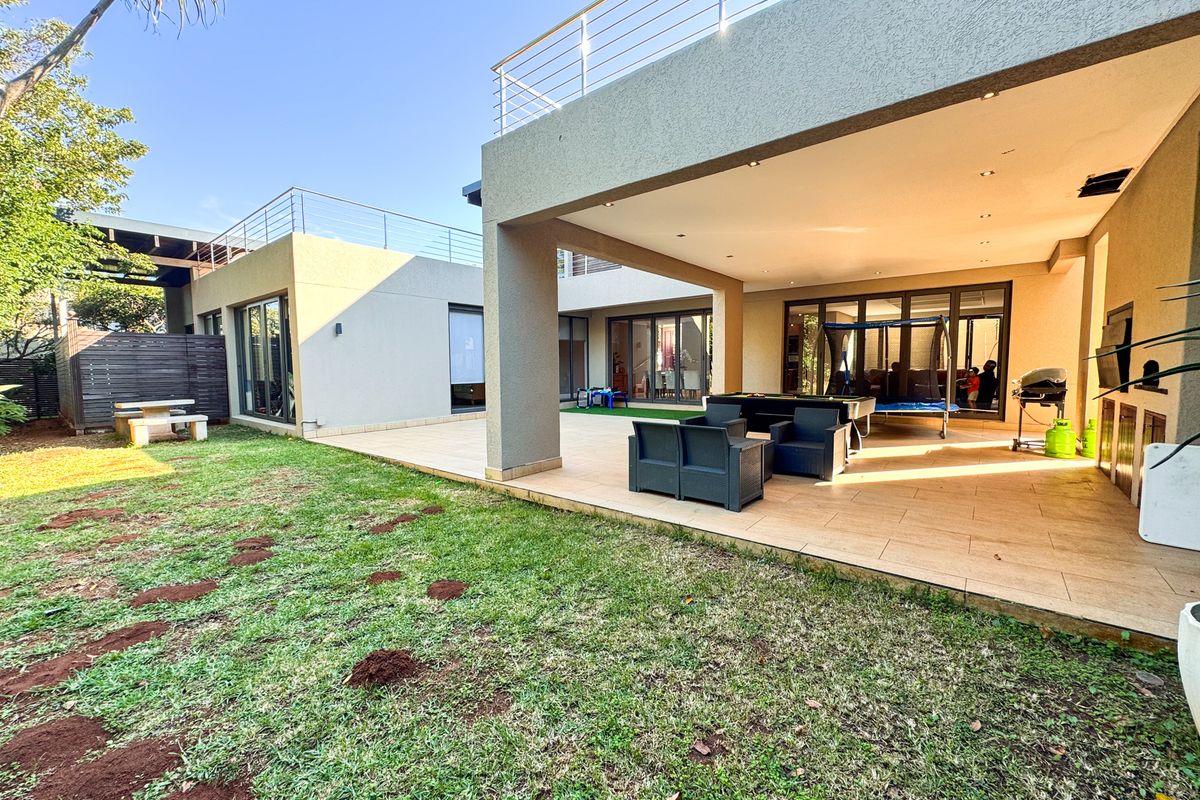 Spacious covered rear patio with tiled flooring and recessed lighting, overlooking a private garden with access to the main living areas via sliding doors.
