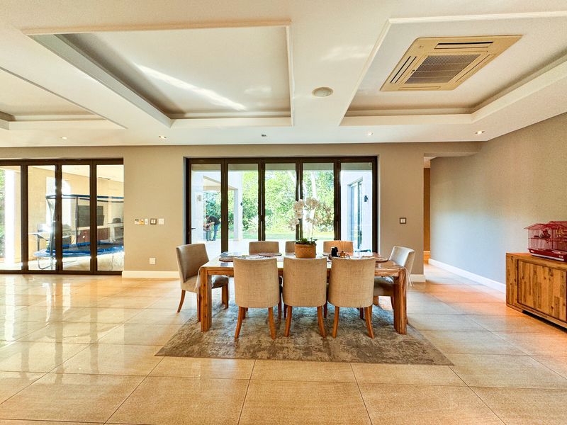 Spacious dining area featuring large bi-fold glass doors leading to the patio, recessed ceiling details, and integrated ducted air conditioning.