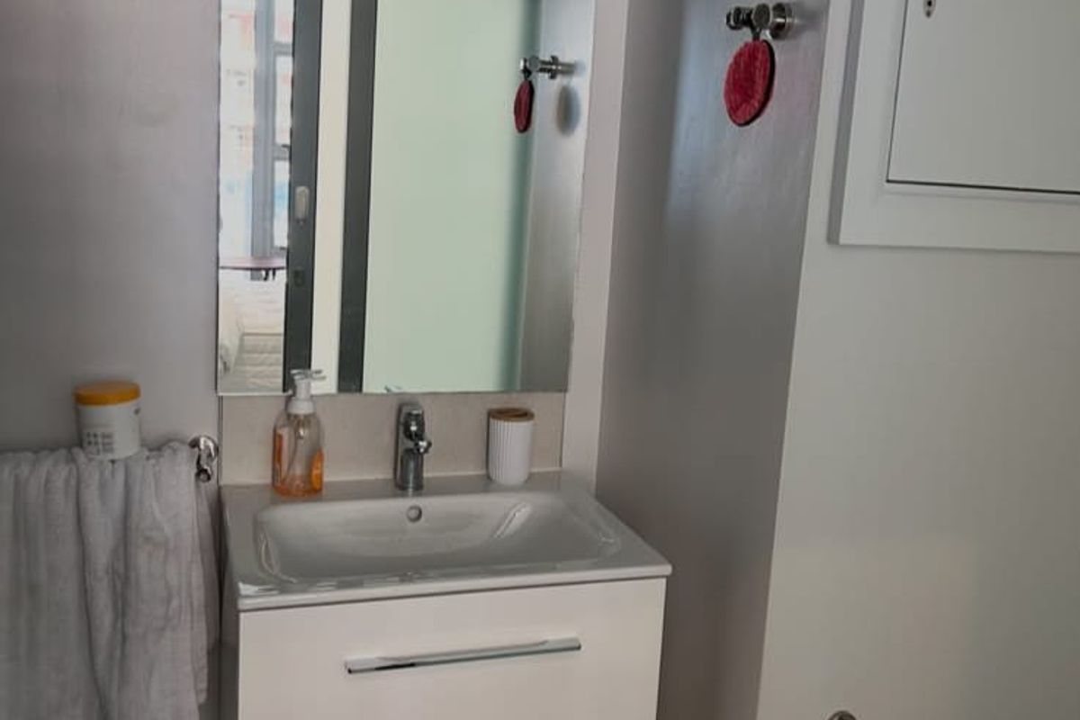 A modern bathroom featuring a wall-mounted vanity with an integrated basin, chrome fixtures, and a large wall mirror.